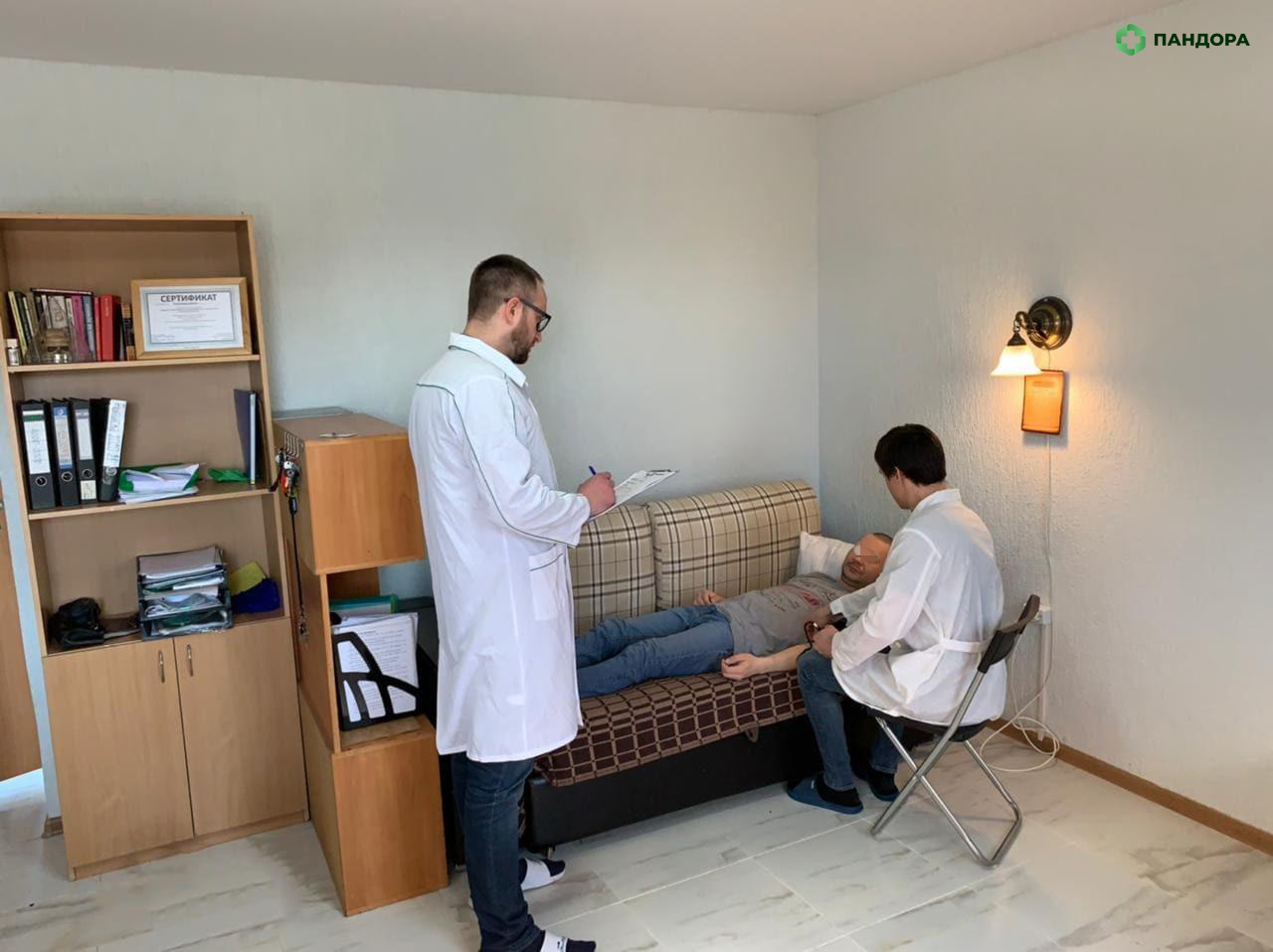 Два врача мужчины лечат пациента